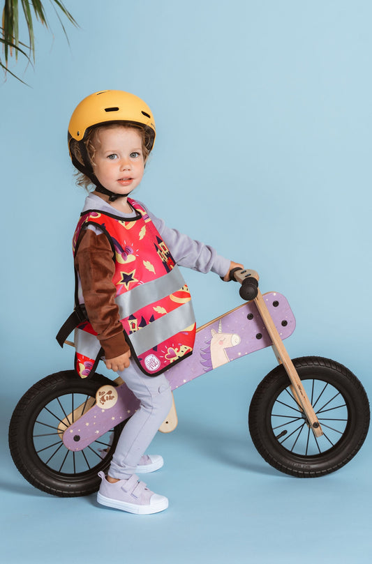 little girl on a bike wearing a pink reflective safety vest